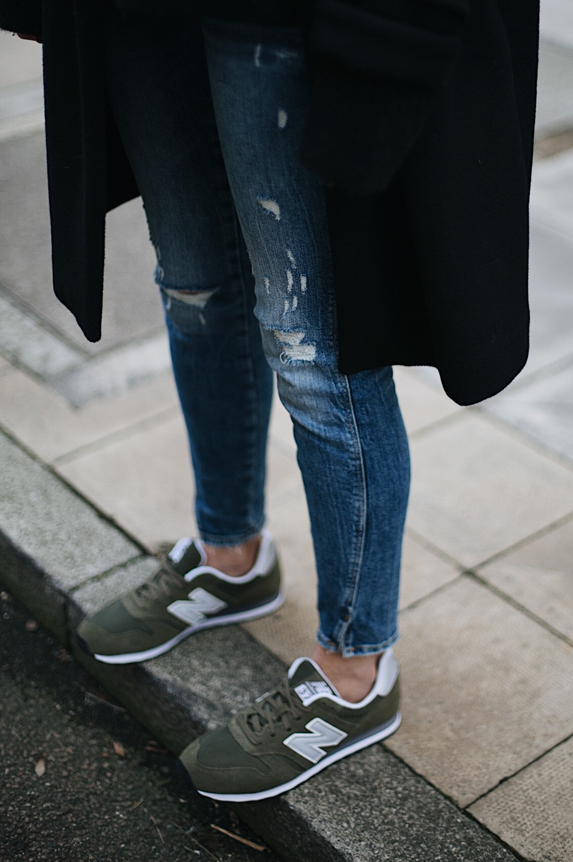 black coat, ripped skinny jeans, khaki new balance trainers