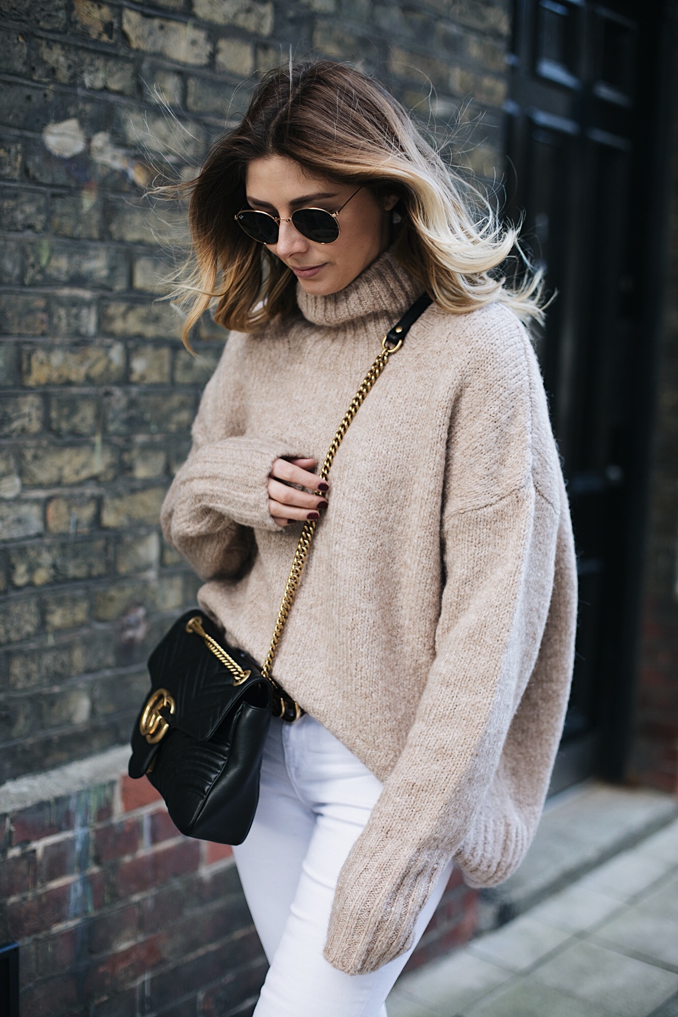Emma Hill wears beige chunky knit, white skinny jeans, Black leather Gucci Marmont bag medium, gold frame round Rayban sunglasses, chic winter outfit