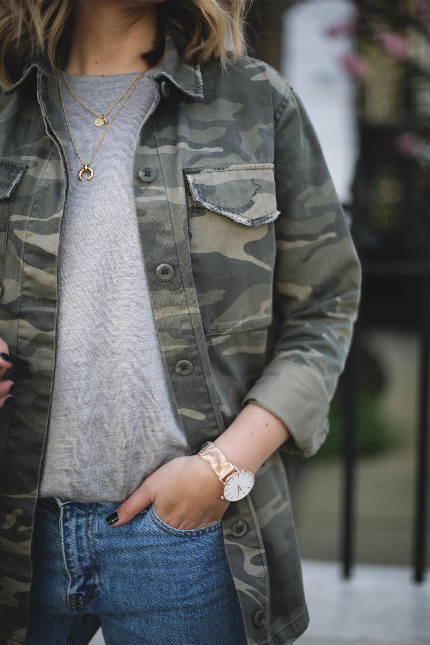 Emma Hill wears camouflage jacket, grey linen t-shirt, light wash jeans, rose gold watch, gold jewellery, casual Spring outfit