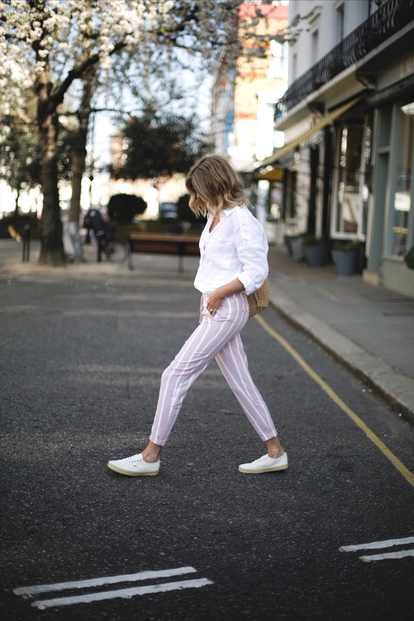 Emma Hill wears pink stripe trousers, white linen shirt, woven basket bag, Vans espadrille lace ups, Ray Ban round metal sunglasses, casual spring summer outfit
