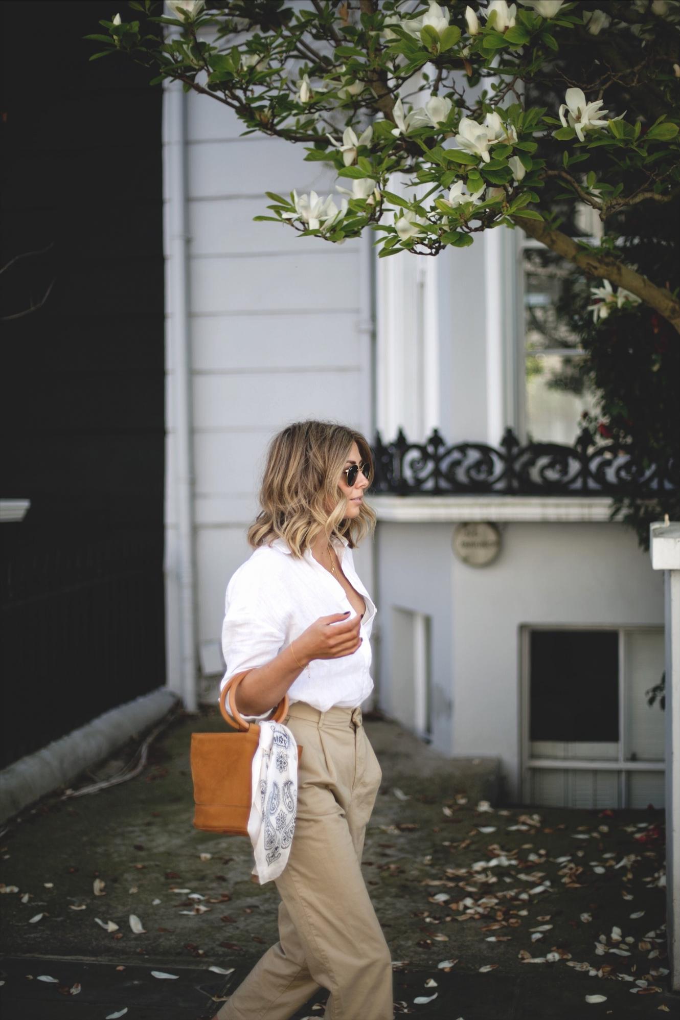 Emma Hill wears white linen shirt, beige chinos, natural wedge espadrilles, tan suede Simon miller bonsai bag with ring handle, chic spring outfit