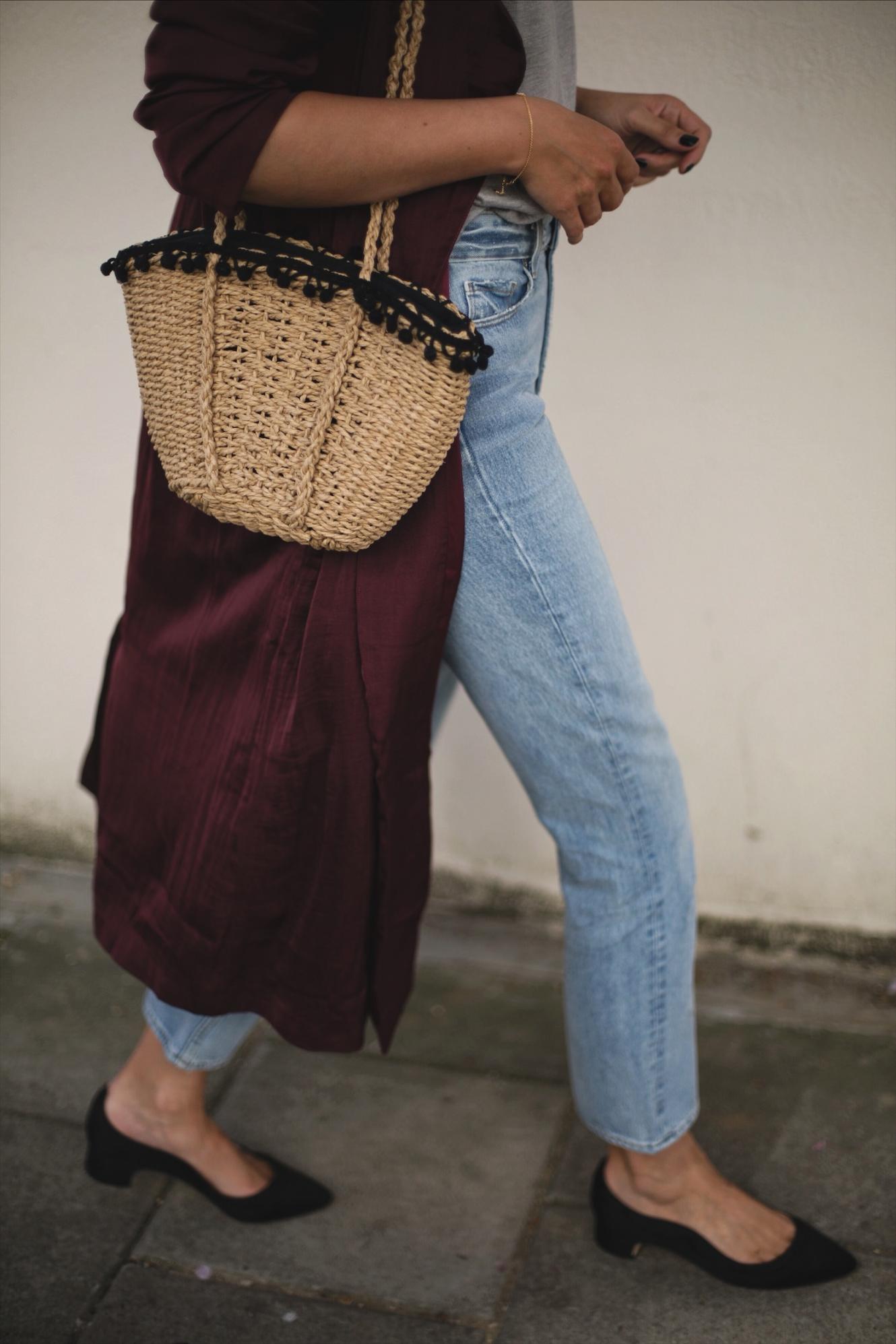 straw basket bag with pom pom detail, light wash straight leg jeans, long deep purple silky duster jacket kimono, black satin Dune x Rupert Sanderson low block heels