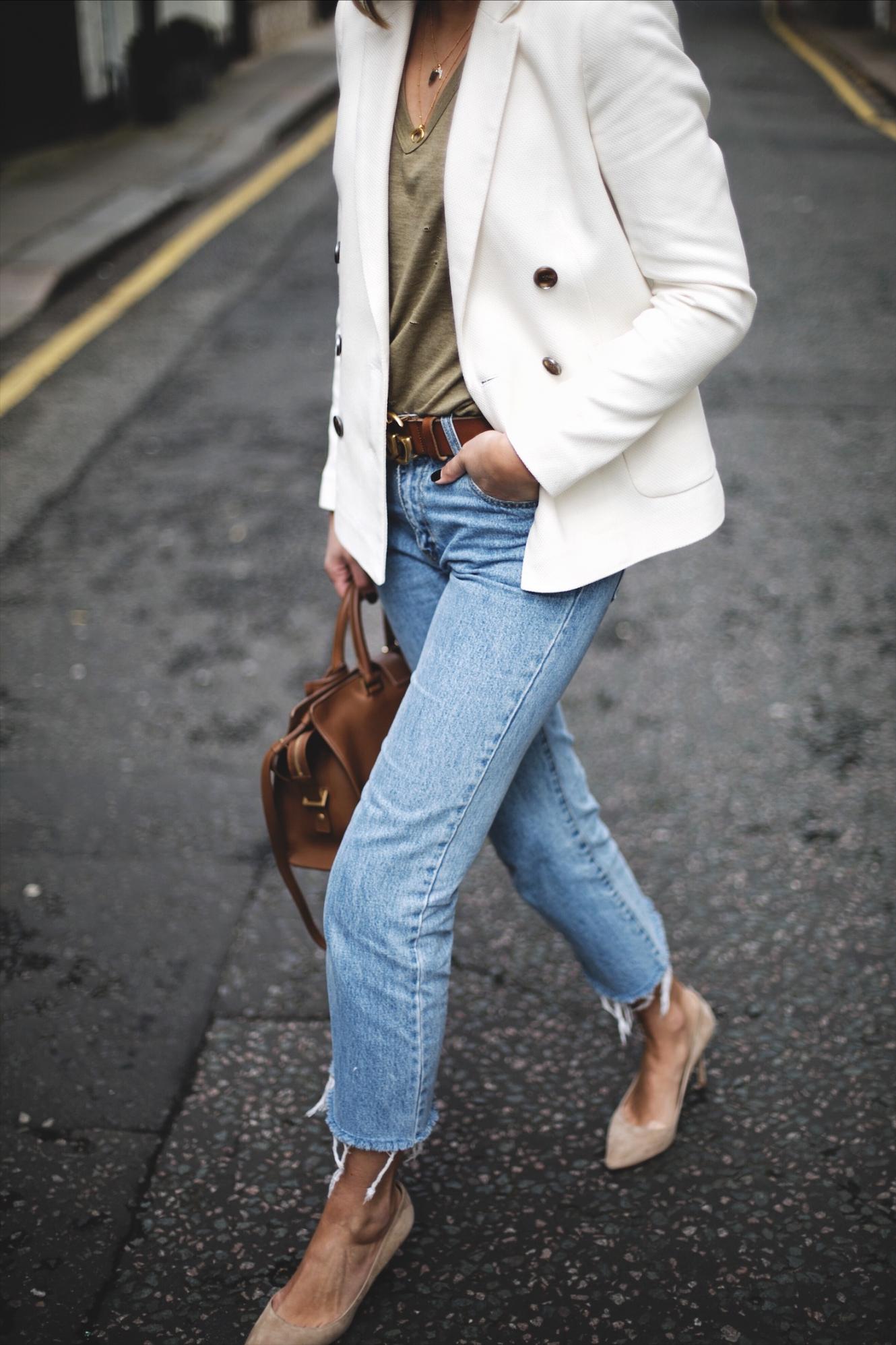 Emma Hill wears off white double breasted blazer, khaki nibbled t-shirt, frayed hem cropped jeans, beige suede Jimmy Choo Romy pumps, YSL Saint Laurent Cabas Chyc in tan leather, tan Gucci GG Marmont belt, gold Missoma necklaces, chic spring outfit