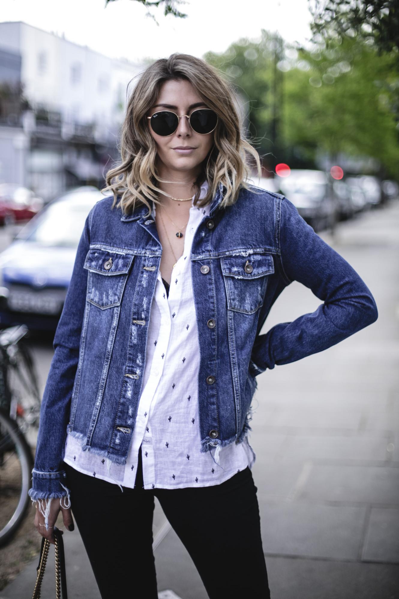 Emma Hill wears Paige frayed denim jacket, Rails white linen cactus print shirt, black lace bra, layered gold necklaces, gold Ray-Ban round metal sunglasses