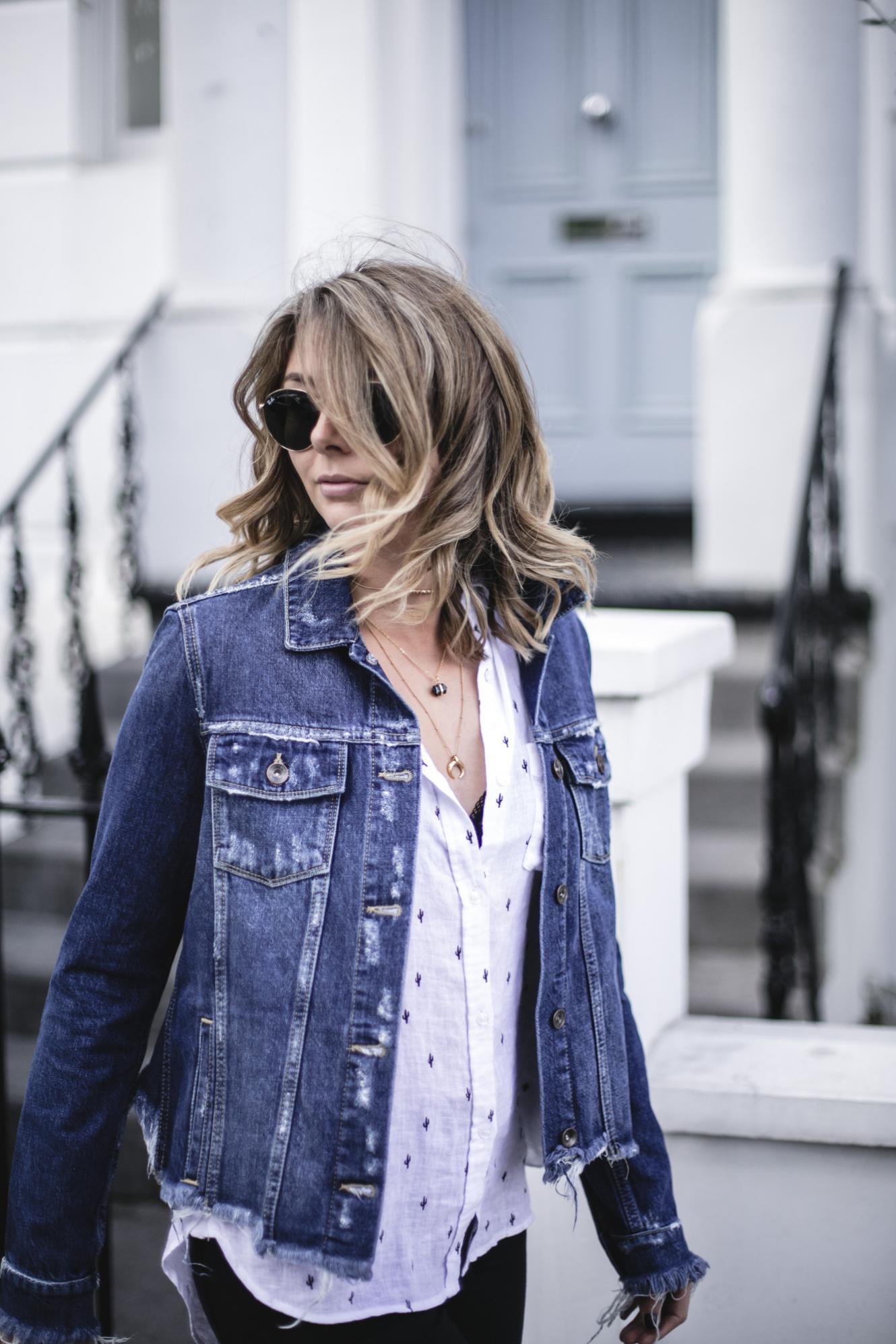Emma Hill wears Paige frayed denim jacket, Rails white linen cactus print shirt, black lace bra, layered gold necklaces, gold Ray-Ban round metal sunglasses