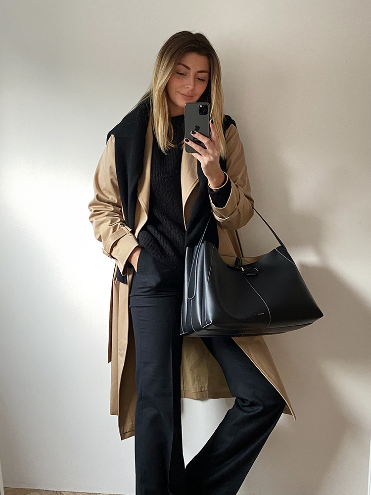 Tan trench coat, black jumper, jumper worn over shoulders, Wandler Ava bag large, flare wool trousers. Chic winter outfit