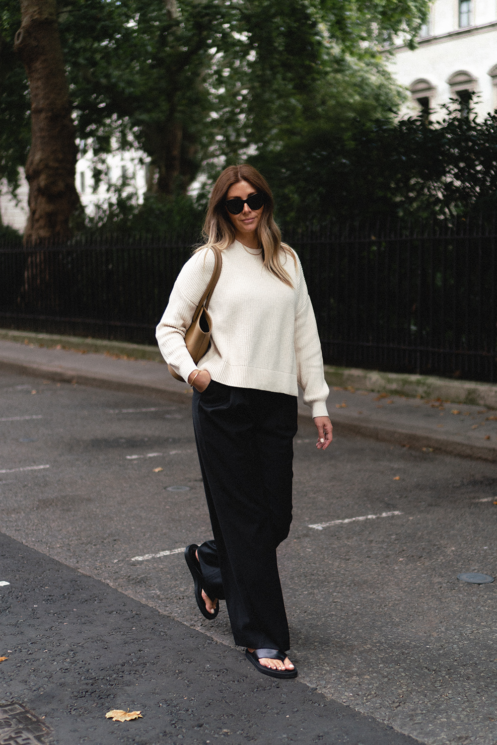 Emma Hill wears cream knitted jumper, blackk wide leg tailored trousers, black leather thong sandals, Little Liffner tall Tulip tote bag. Transitional Summer to Autumn outfit