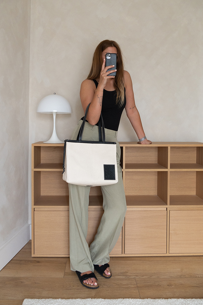 Emma Hill style. Green tailored trousers, black basic vest top, Loewe cushion tote bag, black birkenstock arizona suede sandals.. Minimal Summer outfit