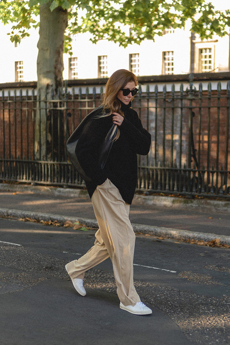 BLOG Emma Hill style. Black cashmere chunky sweater jumper, beige silk tailored trousers, white Veja Esplar trainers, The Row Everyday bag. Minimal Autumn Fall outfit