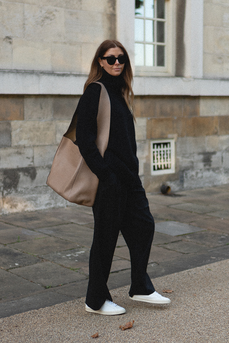 BLOG Emma Hill style. All black outfit. Celine sunglasses, black wide leg tailored trousers, cashmere roll neck jumper, beige leather slouchy hobo bag, white Veja Esplar trainers. Casual minimalist outfit