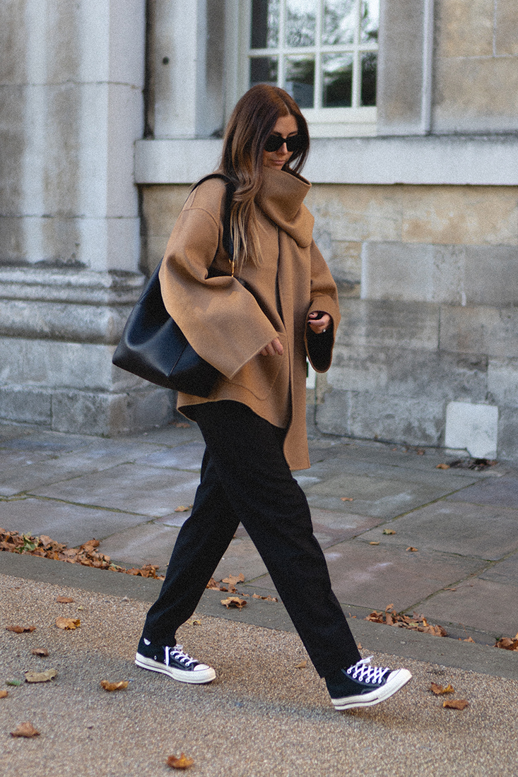 BLOG Emma Hill style. Toteme Camel wool jacket with attached scarf, black trousers, Converse Chuck 70 high tops in black, Celine Seau Sangle bag. Minimal casual autumn fall outfit