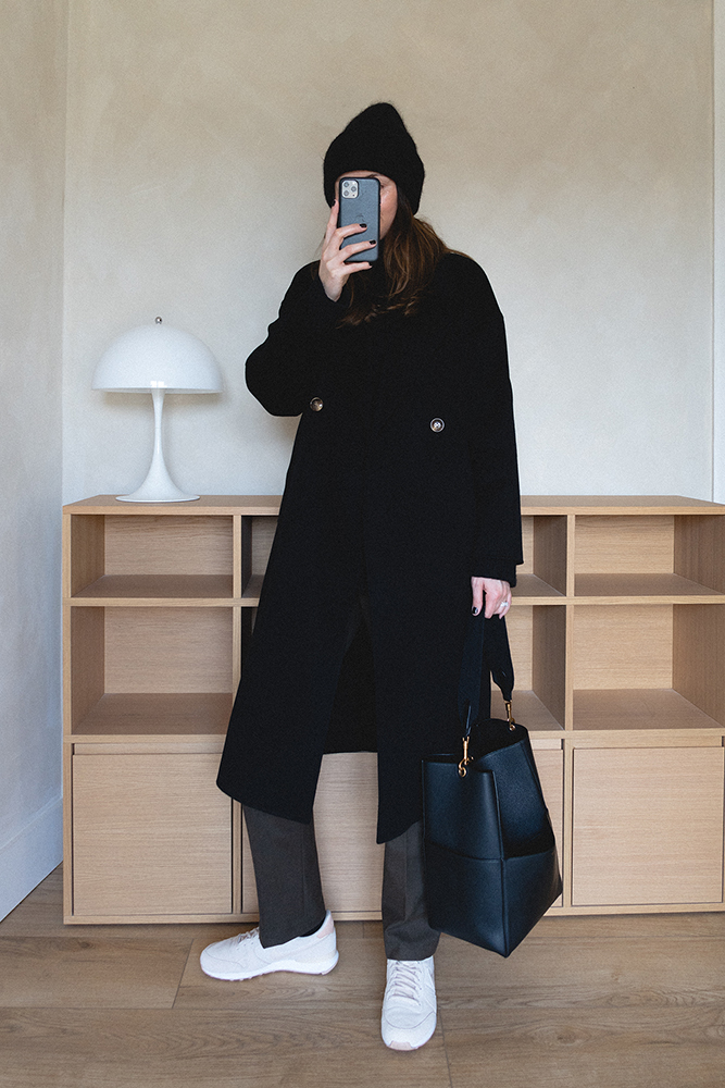 Emma Hill style. Autumn Winter outfit. Black bean hat, black wool coat, black cashmere chunky jumper, green tailored trousers, Celine Seau Sangle bag, Nike internationalist trainers. Minimal style