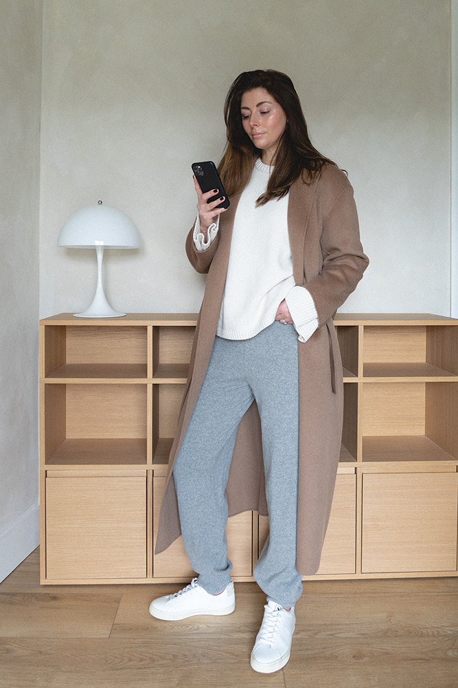 Emma Hill style. Camel belted coat, grey cashmere joggers, white trainers, white jumper. Casual winter outfit. Minimal style